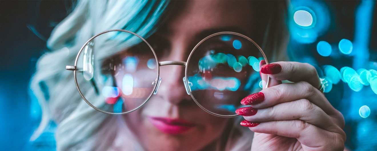 Ragazza bionda che tieni gli occhiali da vista in primo piano
